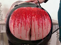 Hefty BBW chick in wearing leather mask bends over the table and gets her ass caned by sultry redhead mistress. Then she pours hot wax on that big ass.