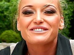 Arousing pretty blonde babe Kathia Nobili with heavy make up and smoking hot body in tight jeans and black shirt gets filmed in close up in backyard and reveals round firm boobs.