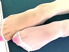 Pretty brunette nurse Sophie Lynx with heavy make up and pierced belly button in white pantyhose and blue stripper shoes touches her body and plays with feet during lunch break.