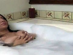 Playful brunette with engaging smile strips her clothes off in a bathroom and takes a bubble bath. Then she also fondles her wet pussy in close-up scenes.