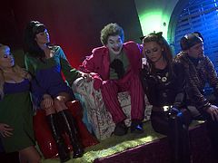A man is wearing clown costume. Women are wearing super hero costumes. The whole scene is funny and edgy. But the scene changes to steamy FFM fuck scene a bit later.
