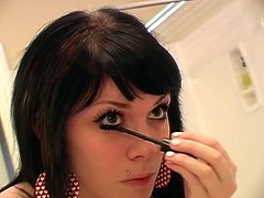 Beautiful brunette applies her make up in front of a mirror
