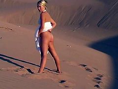 A sweet girl in a white dress lies on sand. She shows her juicy boobs and booty. Later on she takes the dress off and walks around.