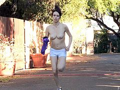 A brunette girl jogs around a neighborhood. It is very hot out there, so she takes off her clothes and jogs being naked. Then she sits down on a bench and fingers herself.