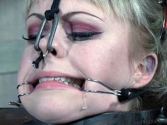 Anna is imprisoned here at Infernal Restraints, and her main pains are coming from the hooks attached to lines, that are currently pulling her mouth and nose. She gets re-positioned later, although it's unknown what will happen to her then.