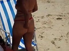 Na praia de bikini minusculo mamas  exibem